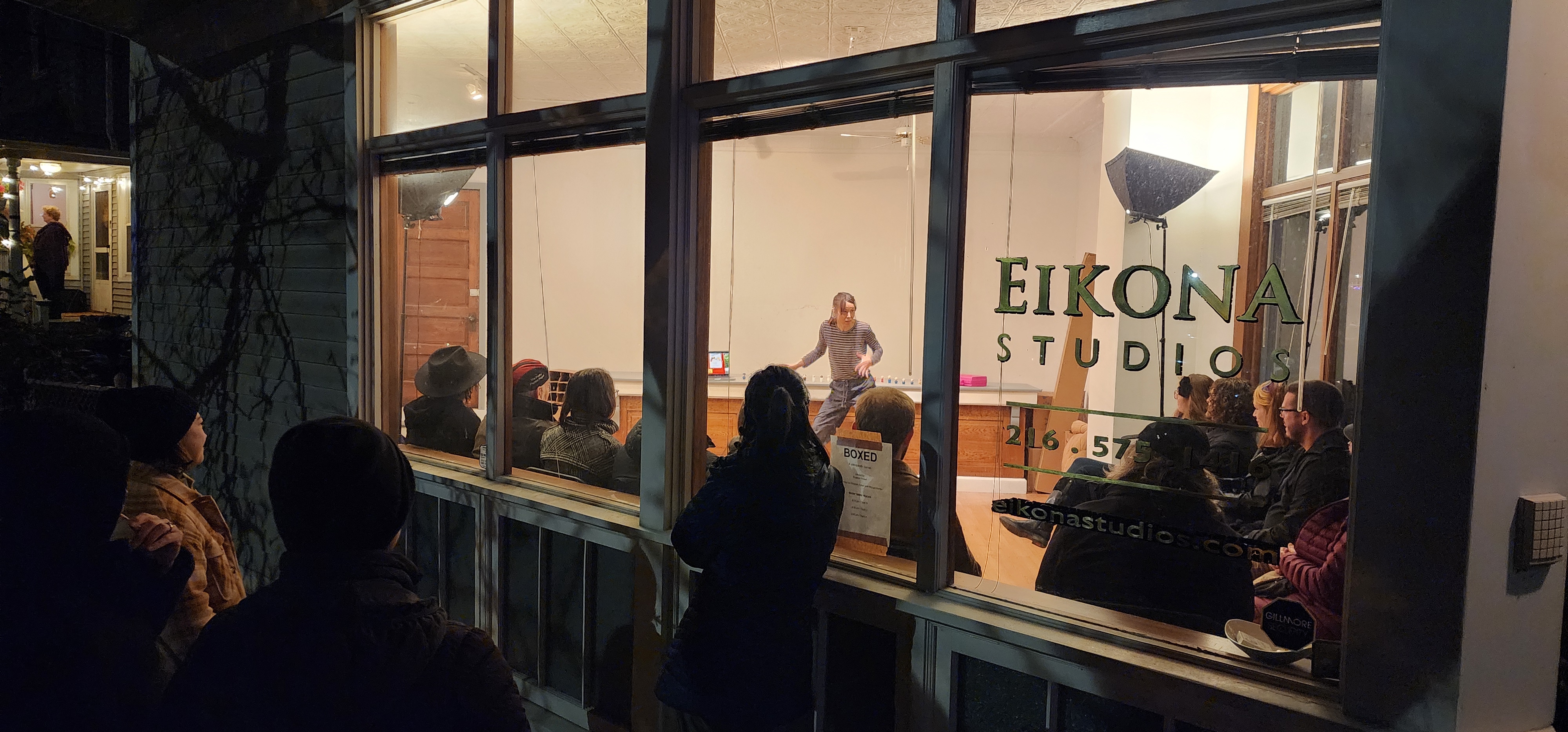 Performance viewed through storefront window at Eikona Studios